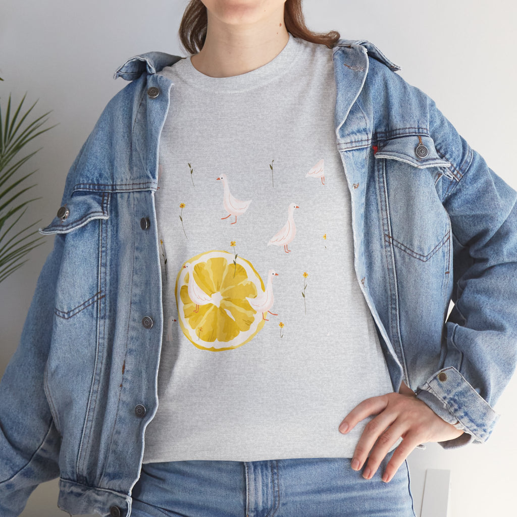 A girl wearing a denim jacket over a grey t-shirt featuring a colorful design of white ducks covering the shirt with a juicy lemon in the bottom-left corner.