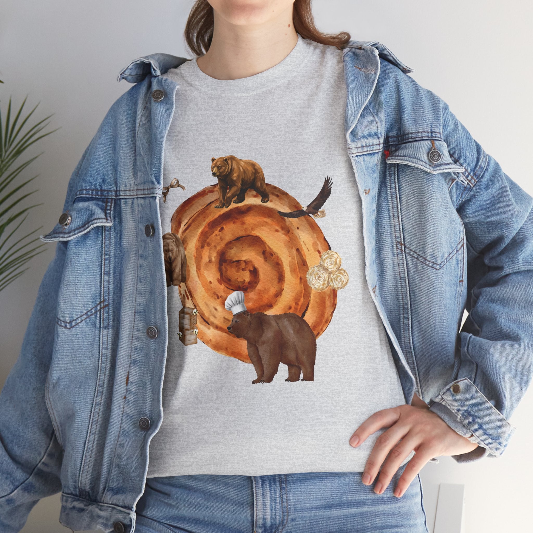 A girl wearing a denim jacket over a grey t-shirt featuring a colorful design of a cinnamon roll surrounded by several hungry bears.